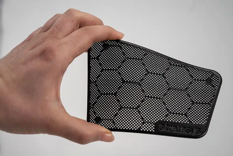Technician holding shot peened SLS speaker grill part to show surface detail and finish consistency
